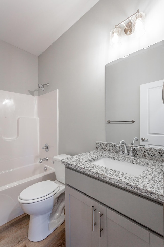 bathroom with toilet,  shower combination, wood finished floors, and vanity