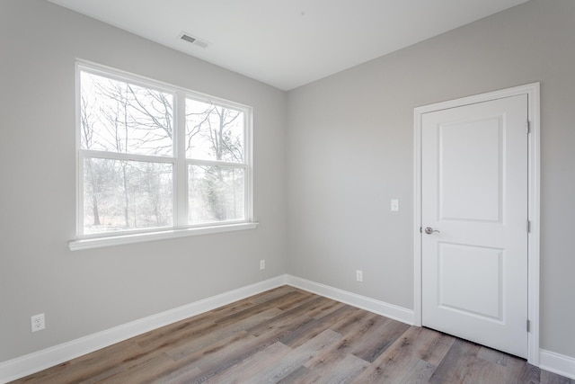 spare room with visible vents, baseboards, and wood finished floors