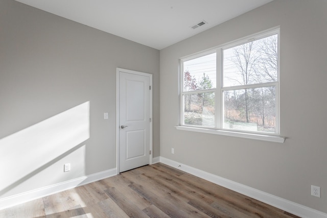 unfurnished room featuring visible vents, baseboards, and wood finished floors