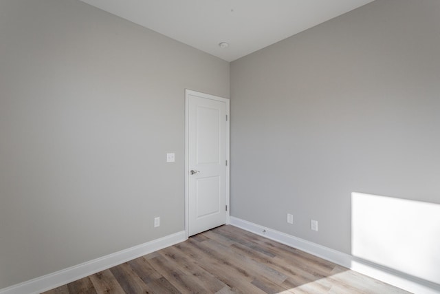 spare room with baseboards and wood finished floors