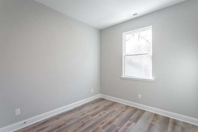 unfurnished room featuring visible vents, baseboards, and wood finished floors