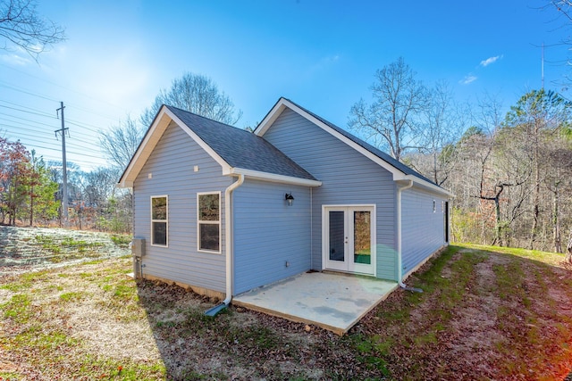 rear view of house with a patio area and roof with shingles