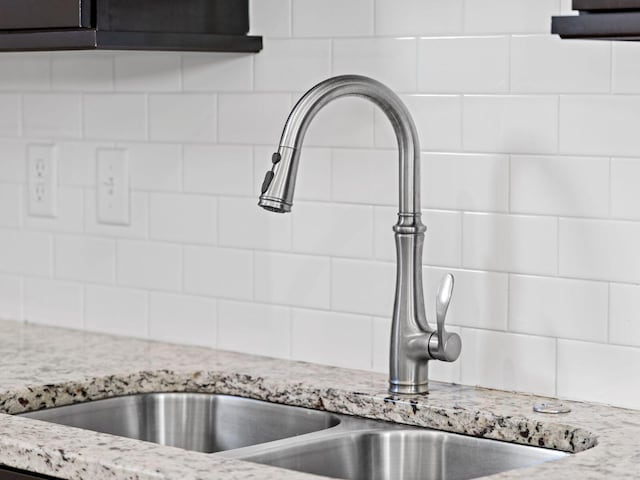 room details with light stone counters, decorative backsplash, and a sink