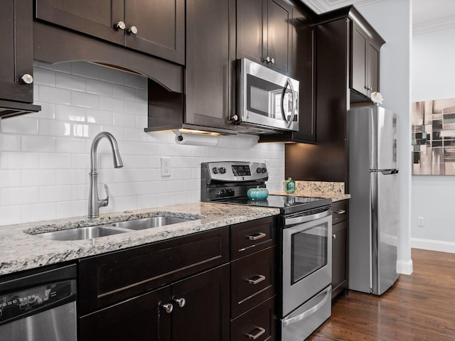 kitchen with a sink, appliances with stainless steel finishes, decorative backsplash, light stone countertops, and dark wood-style flooring