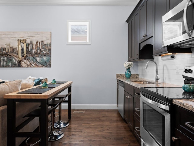 kitchen with decorative backsplash, light stone countertops, appliances with stainless steel finishes, and a sink