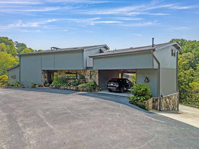 exterior space featuring a carport, stone siding, and driveway