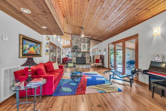 living area featuring a stone fireplace, french doors, lofted ceiling, and wood finished floors