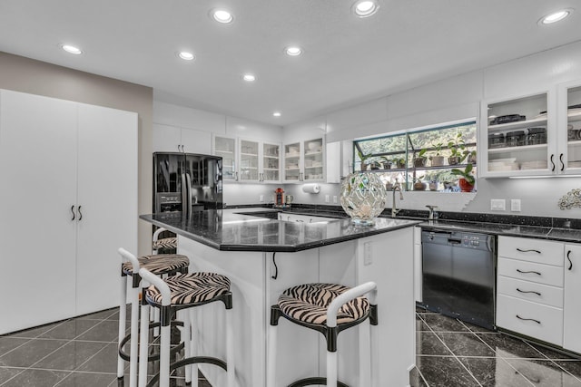 kitchen with white cabinetry, a kitchen breakfast bar, black appliances, and glass insert cabinets