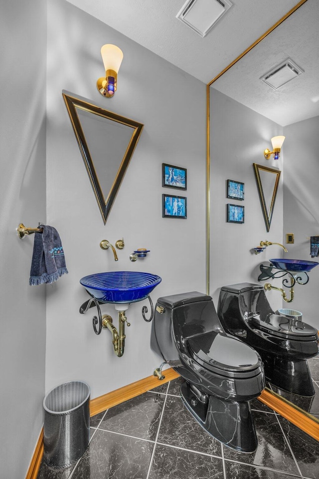 half bathroom with visible vents, marble finish floor, and toilet