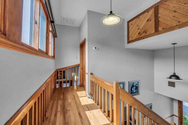 corridor with an upstairs landing, visible vents, and wood finished floors