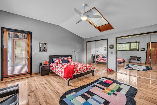 bedroom featuring ceiling fan, wood finished floors, multiple closets, and vaulted ceiling