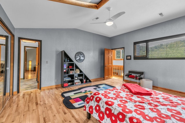 bedroom featuring visible vents, baseboards, wood finished floors, and vaulted ceiling