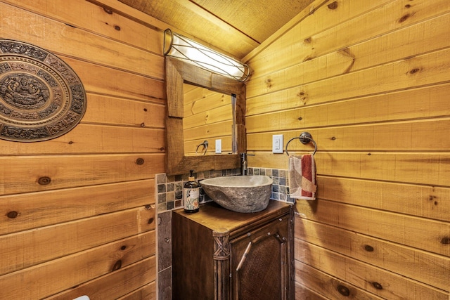 bathroom featuring wood walls, vanity, and lofted ceiling