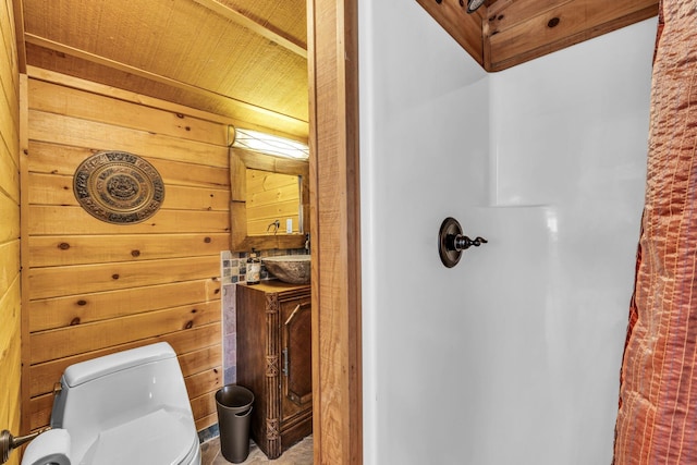 bathroom featuring wooden walls, vanity, toilet, and a shower