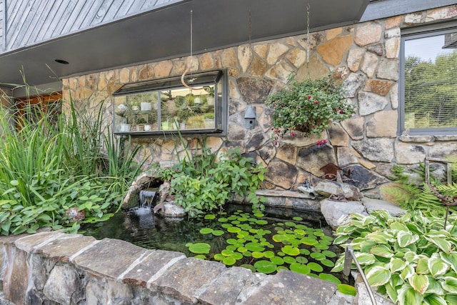 exterior details with stone siding and a small pond