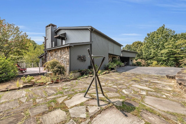 view of side of home with stone siding and a chimney