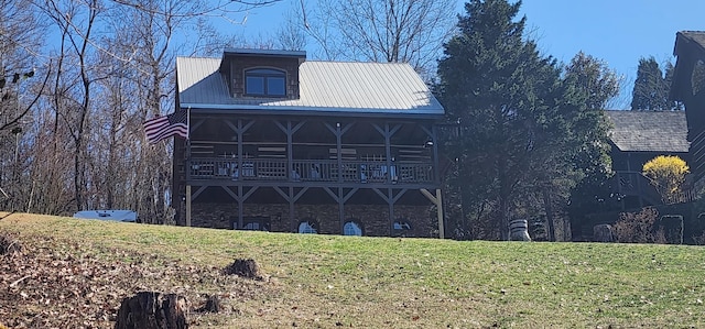 back of property with stone siding, a lawn, and metal roof