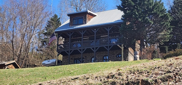 rear view of property with a yard, stone siding, and metal roof