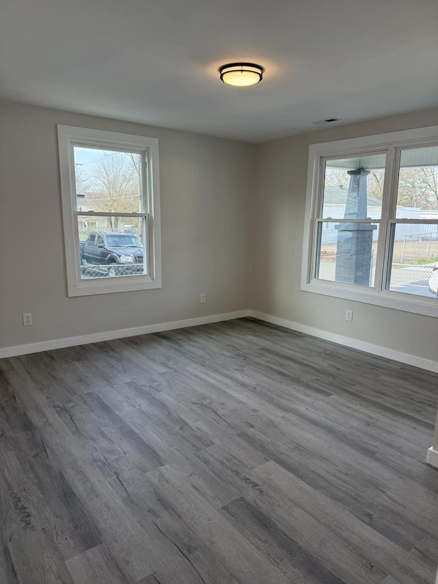 spare room featuring visible vents, baseboards, and dark wood-style flooring