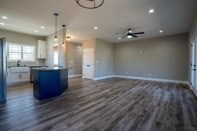 kitchen featuring baseboards, recessed lighting, a sink, white cabinets, and dark countertops