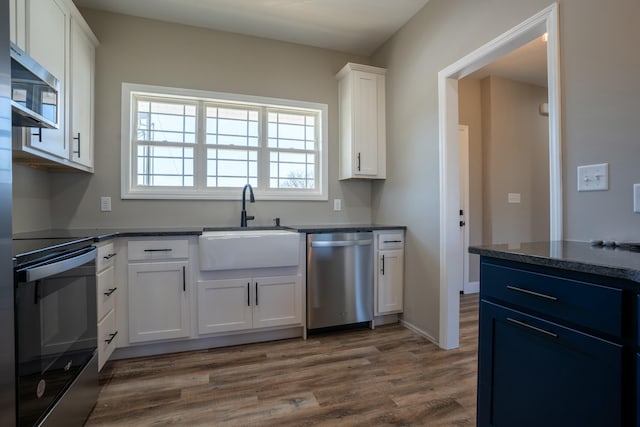 kitchen with a sink, dark countertops, dark wood-style flooring, and stainless steel appliances