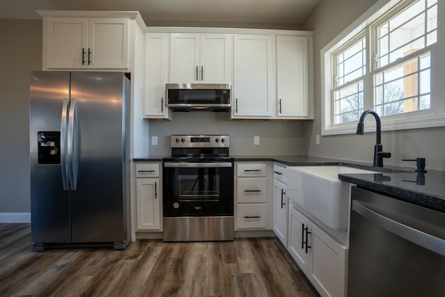 kitchen with dark wood finished floors, white cabinets, stainless steel appliances, and a sink