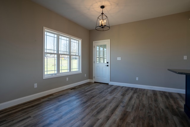 interior space featuring dark wood-type flooring, a notable chandelier, visible vents, and baseboards