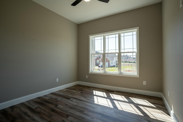 empty room with dark wood-type flooring, baseboards, visible vents, and ceiling fan