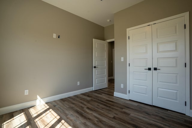 unfurnished bedroom featuring a closet, baseboards, and dark wood finished floors