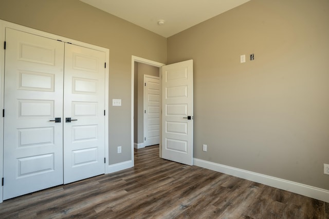 unfurnished bedroom featuring a closet, baseboards, and dark wood-style floors