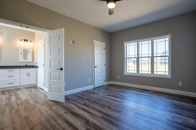 unfurnished bedroom with a sink, baseboards, and dark wood-style floors