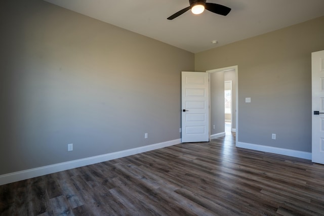 unfurnished room with dark wood finished floors, a ceiling fan, and baseboards