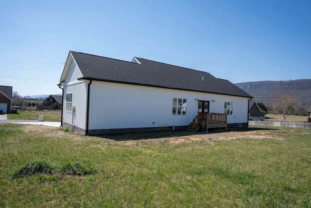 rear view of house with crawl space, a lawn, and a shingled roof