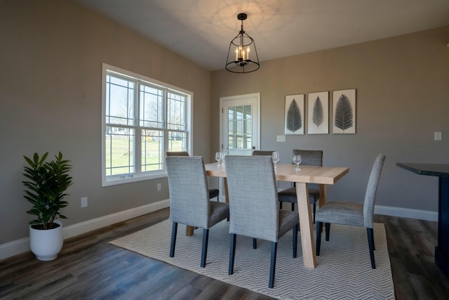 dining area with a chandelier, dark wood-type flooring, and baseboards