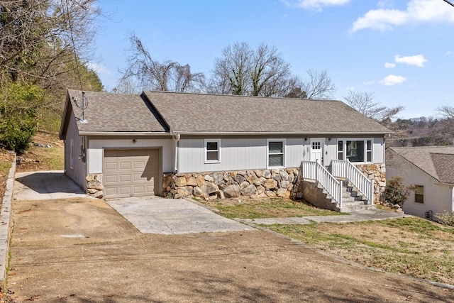 single story home with concrete driveway, an attached garage, stone siding, and a shingled roof