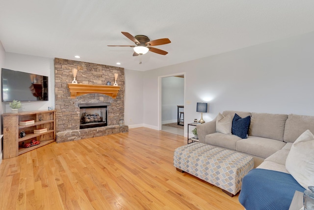 living room featuring a fireplace, baseboards, ceiling fan, and wood finished floors