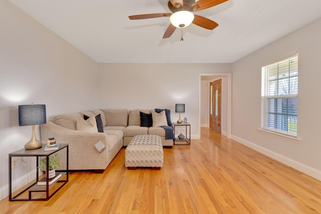 living room featuring baseboards, light wood-style floors, and a ceiling fan