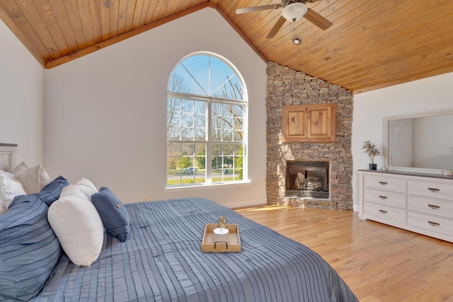 bedroom featuring wood ceiling, a stone fireplace, wood finished floors, high vaulted ceiling, and a ceiling fan