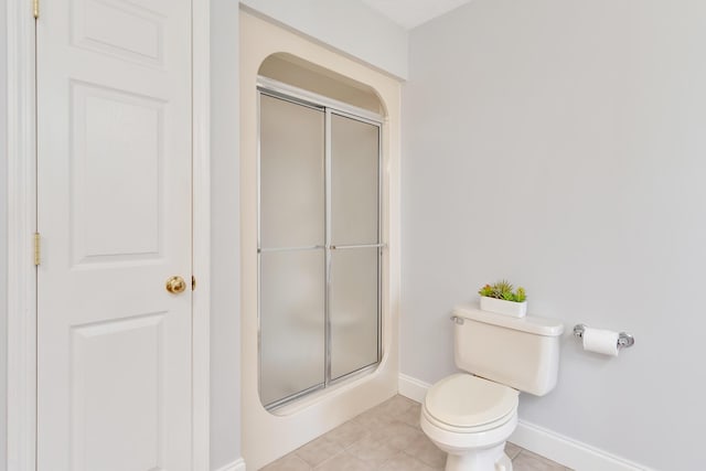 bathroom featuring tile patterned floors, baseboards, toilet, and a stall shower