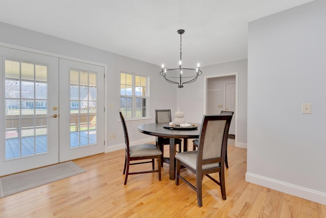 dining area with light wood-type flooring, baseboards, a chandelier, and french doors