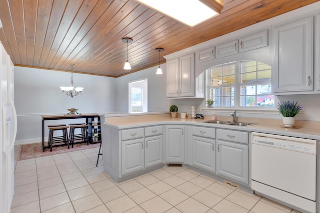 kitchen featuring white appliances, light tile patterned floors, a peninsula, and a sink