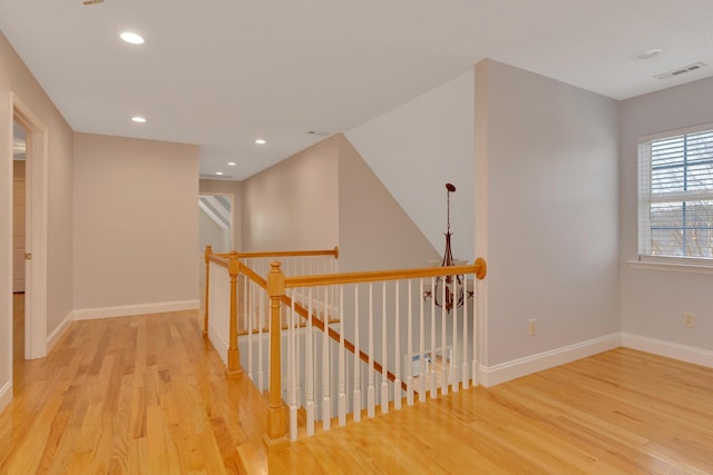 corridor with visible vents, baseboards, and wood finished floors