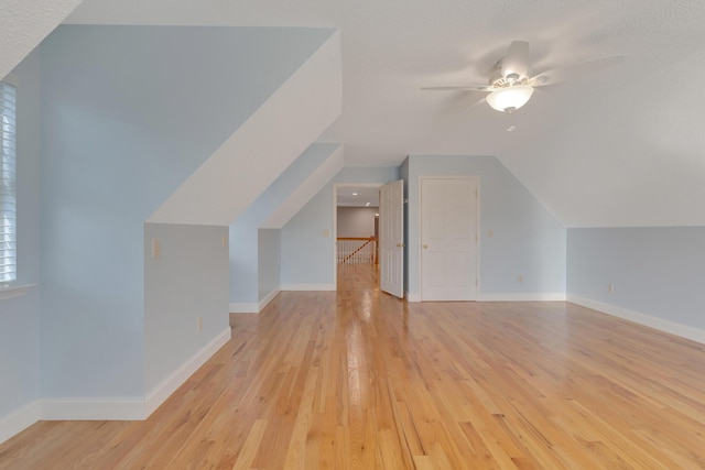 additional living space featuring light wood-style flooring, lofted ceiling, and baseboards