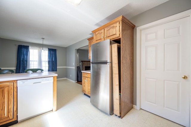 kitchen featuring baseboards, light floors, dishwasher, light countertops, and freestanding refrigerator