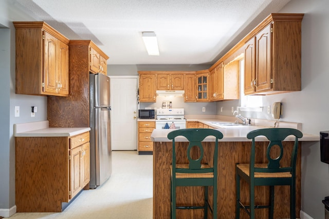 kitchen featuring black microwave, light floors, freestanding refrigerator, white electric range, and a sink