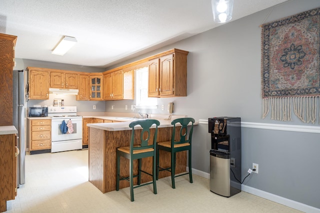 kitchen featuring black microwave, under cabinet range hood, light floors, a peninsula, and electric range