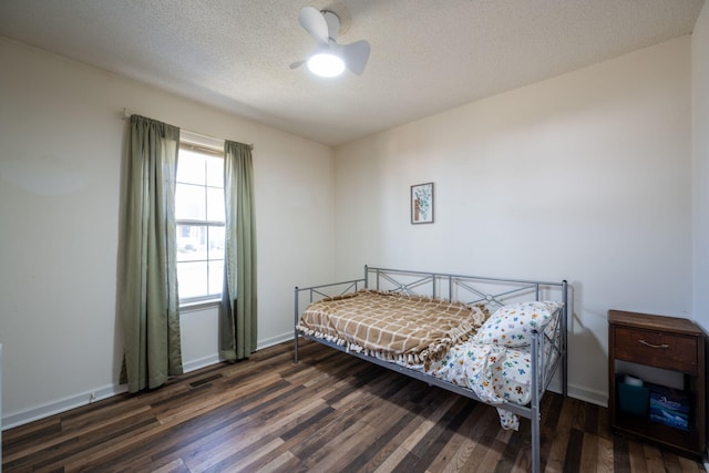 bedroom with visible vents, baseboards, a textured ceiling, and wood finished floors