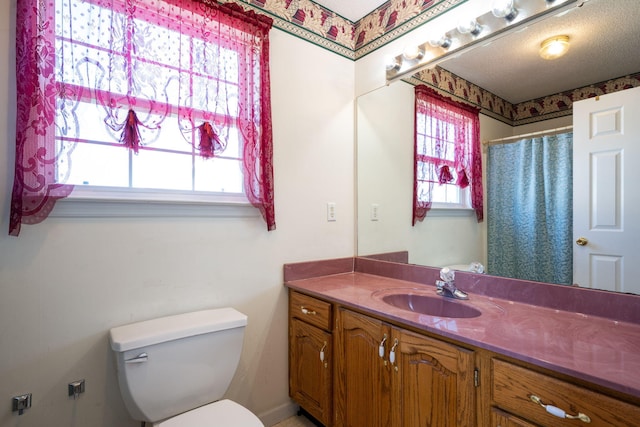 bathroom featuring a healthy amount of sunlight, a textured ceiling, toilet, and vanity