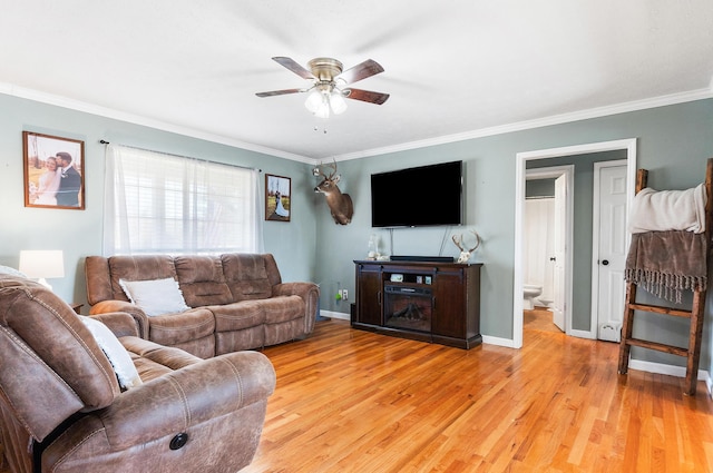 living area with light wood-type flooring, baseboards, ceiling fan, and ornamental molding