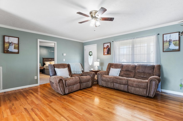 living room featuring crown molding, baseboards, light wood-type flooring, and ceiling fan